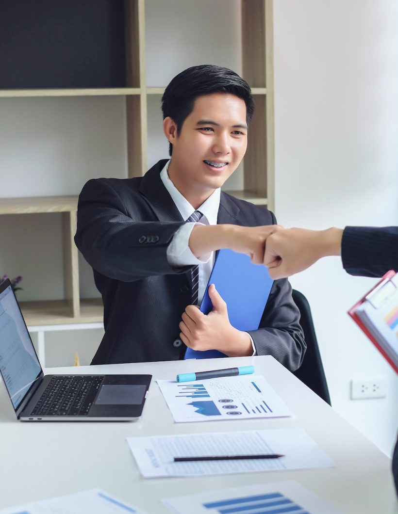 Young asian businessman partners fist bump showing cooperation and success at work.